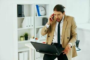 man in beige jacket in the office with a laptop executive photo