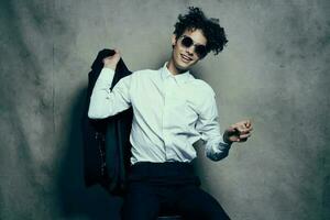 stylish guy in a suit sits on a chair indoors and glasses on his face photo