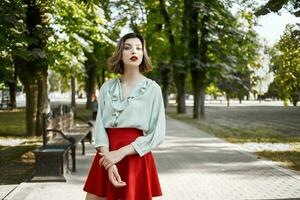 pretty woman in red skirt walking in the park trees fresh air posing photo