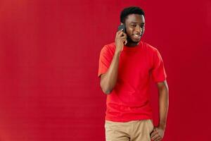 African American in a red t-shirt with a phone in his hands communicates photo