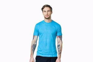 athlete with dumbbells on a light background and blue t-shirt pants tattoo photo