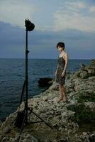 hermosa mujer en pie en piedras posando en playa vestir lujo inalterado foto