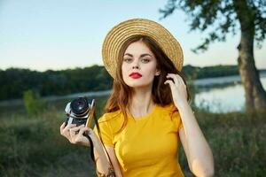 mujer en un sombrero con un cámara en su manos rojo labios atractivo Mira naturaleza foto