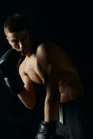 boxer in black gloves bent down on a dark background bodybuilder fitness photo