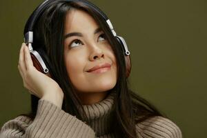 Brunette in a sweater listening to music with headphones fun studio model photo