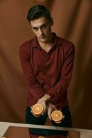 Handsome man fashionable hairstyle red shirt oranges in hands fabric background photo