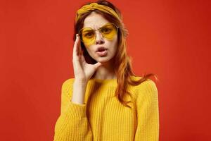 bonito mujer en amarillo suéter lentes Moda emociones rojo antecedentes foto