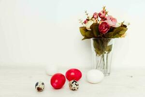 painted Easter eggs on the table and a bouquet of flowers in the background In a bright room photo