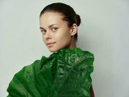 pretty woman with green leaf of palm tree on light background cropped view photo