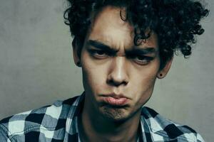 emocional chico en un tartán camisa en un gris antecedentes riendo Confusión tristeza incertidumbre foto