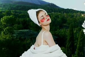 a fit girl stands in a robe against the backdrop of mountains with patches on his face close-up photo