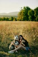 mujer sentado en campo con perro tejonero perro sonriente mientras gasto hora en naturaleza con amigo perro en otoño a puesta de sol mientras de viaje foto