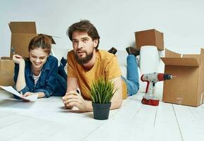 Moving to an apartment a man and a woman lie on the floor and a flower in a pot photo