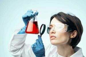 female laboratory assistant looking through a magnifying glass at a chemical solution analysis diagnostics photo