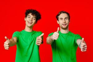 Cheerful friends in green t-shirts gesturing with hands emotions red background photo