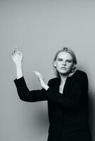 Fashion model girl posing with her hands up in the studio in black and white style in a classic jacket photo