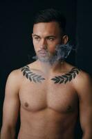 Modelling snapshots. Pensive serious tanned attractive handsome naked man thinking looks aside smoking posing isolated in black studio background. Fashion offer. Copy space for ad. Closeup photo