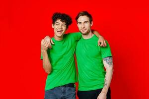 Two man green t-shirts embrace emotions friendship red background photo