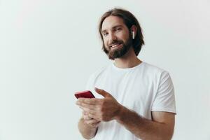 Man blogger holds a phone in his hands and communicates with people online in social networks with a smile and a white t-shirt on a white background photo