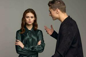 An indignant man in a black jacket gestures with his hands and looks at the woman photo
