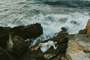 woman lying on rocky coast with cracks on rocky surface view from above photo