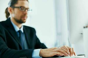 business man with glasses in a suit works at the computer in the office photo