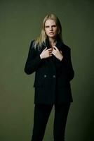 A concept for marketplaces and clothing brands. Full-length portrait of a blonde holding a jacket collar posing on a green background in the studio photo