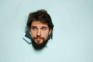 Emotional man peeps his head out of the blue background wall photo