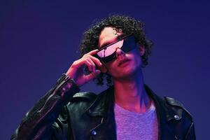 Attractive curly man leather jacket wear mirror glasses looks at camera posing isolated on color pink blue background. Cool fashion offer. Huge Seasonal Sale New Collection concept. Copy space for ad photo