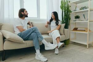 Man and woman friends sitting on the couch and smiling merrily talking to each other having a good time together. Lifestyle in happiness at home photo