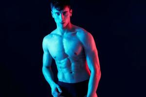 portrait of an attractive guy with a pumped-up torso bodybuilder black background photo