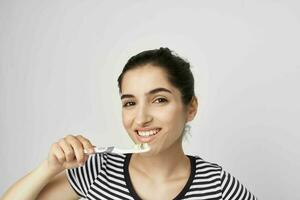 mujer en un a rayas camiseta cepillo de dientes en mano aislado antecedentes foto