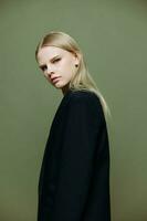 The young model turns and looks at the camera over her shoulder. Cool banner offer. A girl poses in isolation in a suit in a studio with a green background photo