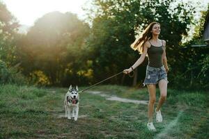 Woman and her husky dog happily running through the grass in nature in the park smile with teeth fall walk with pet, traveling with a dog friend photo