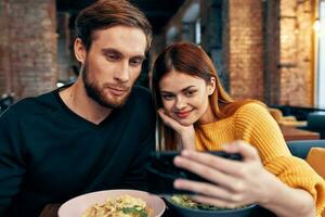 linda hombres y mujer en un restaurante con un teléfono en su manos selfie foto