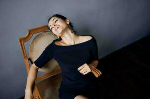 beautiful woman earrings jewelry posing near the chair black dress dark background photo