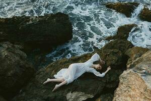 sensual woman in a white dress lying on a stone in a white dress landscape photo