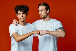 two friends in white t-shirts hugs communication red background photo