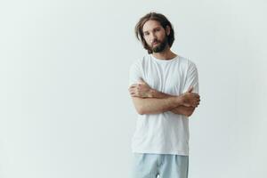 Portrait of a sad man with a black thick beard and long hair in a white t-shirt on a white isolated background photo