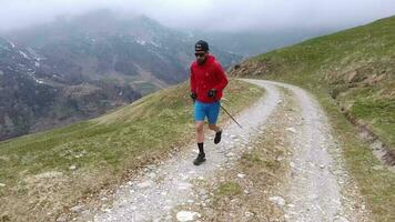 Male athlete runs on dirt road with poles video