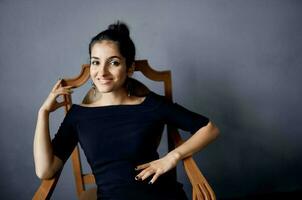 pretty woman earrings jewelry posing near the chair black dress dark background photo