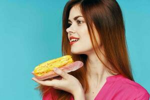 glamorous woman pink shirt with eclairs in the hands of sweets photo