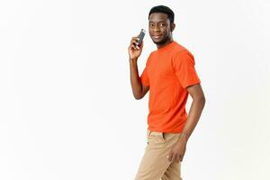 a guy in an orange T-shirt with a mobile phone on a Light background Copy Space photo