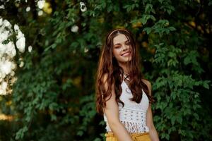 A woman in eco-friendly clothing in a hippie look dances in nature in the park and smiles at the world. The concept of harmony with the body and the surrounding nature photo