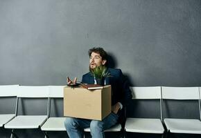 A man with things in a box sits on a chair waiting for discontent photo