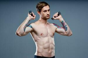 sexy athletic men with dumbbells on gray background and biceps press tattoos photo