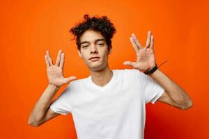 cute guy with curly hair in a white t-shirt gestures with his hands photo