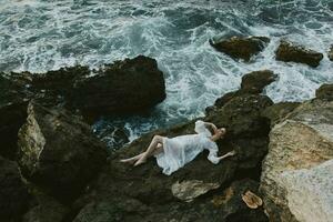 Barefoot woman Lies on his back on a stone cliff, cloudy weather view from above photo