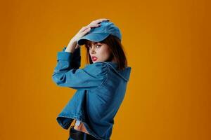 Portrait of a charming lady in a cap and denim jacket posing color background unaltered photo