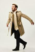 energetic man in a coat runs to the side on a light background and stylish clothes fashion photo